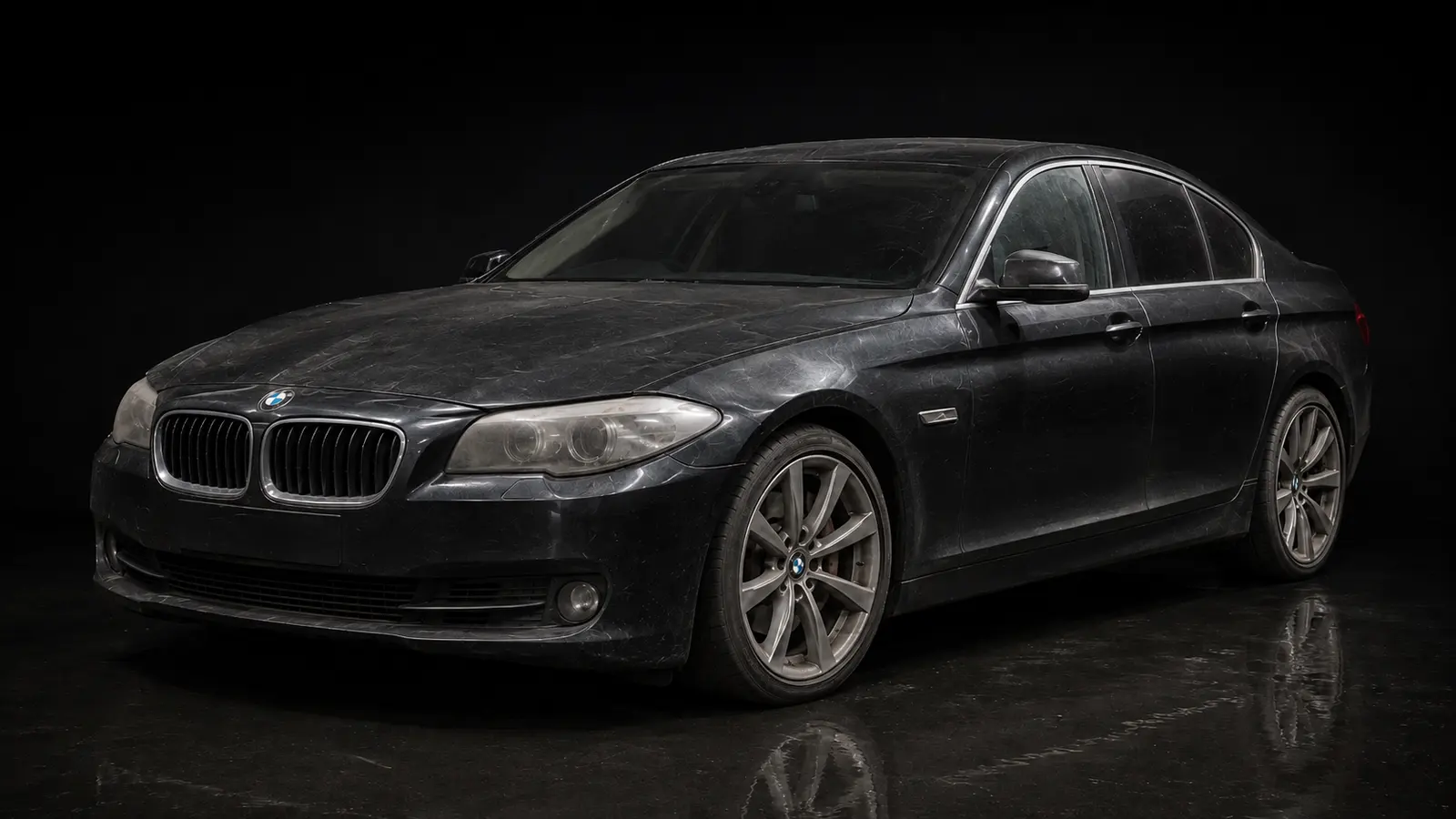 A Sapphire Black BMW 5 Series before detailing — dull, swirled paint holding dust and water spotting.